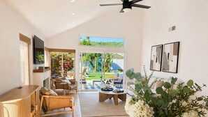 Amplia sala de estar con mesa de centro de madera, sofá de cuero y un ventanal con vistas a un jardín.