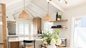 Una cocina moderna con armarios blancos, una isla central y lámparas colgantes.