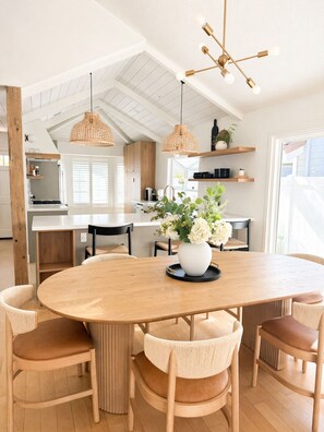 A modern kitchen with white cabinetry, a central island, and hanging pendant lights. - San Clemente Beach Retreat / Fire Pit  Patio  Indoor-Outdoor Living (San Clemente)