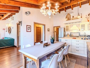 A modern kitchen with white cabinets, a stainless steel refrigerator, and a wooden dining table with chairs. - La Terrazza sul Lago by Interhome (Dervio)