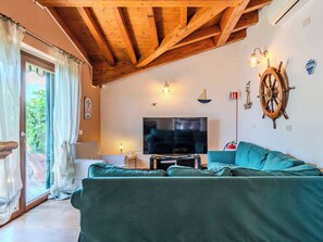 A living room with a wooden ceiling, a television, a sofa, and a wall-mounted ship's wheel. - La Terrazza sul Lago by Interhome (Dervio)