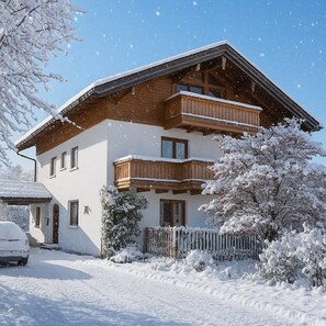 A two-story chalet with a wooden balcony, a snow-covered fence, and a clear sky. - Vacation apartment Gipfelglück 76sqm, balcony, 1 bedroom, WLAN, max. 2 pax, dogs allowed. (Ruhpolding)