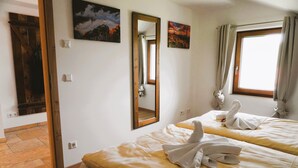 Quarto de hotel com duas camas, piso de madeira, um espelho grande e obras de arte nas paredes.
