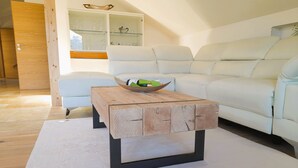Uma sala de estar moderna com uma mesa de centro de madeira, sofá branco e um aparador de vidro.