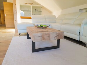 A modern living room with a wooden coffee table, white sofa, and a glass cabinet. - Vacation apartment Gipfelglück 76sqm, balcony, 1 bedroom, WLAN, max. 2 pax, dogs allowed. (Ruhpolding)