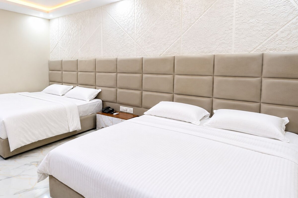 A hotel room with two beds, a marble floor, and a textured wall.