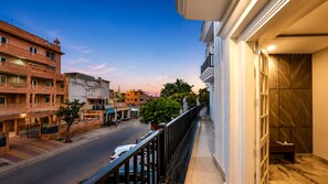 A balcony with a view of a city street, a building with a balcony, and a door with a marble wall. - Hindustan Royal Inn (Haridwar)