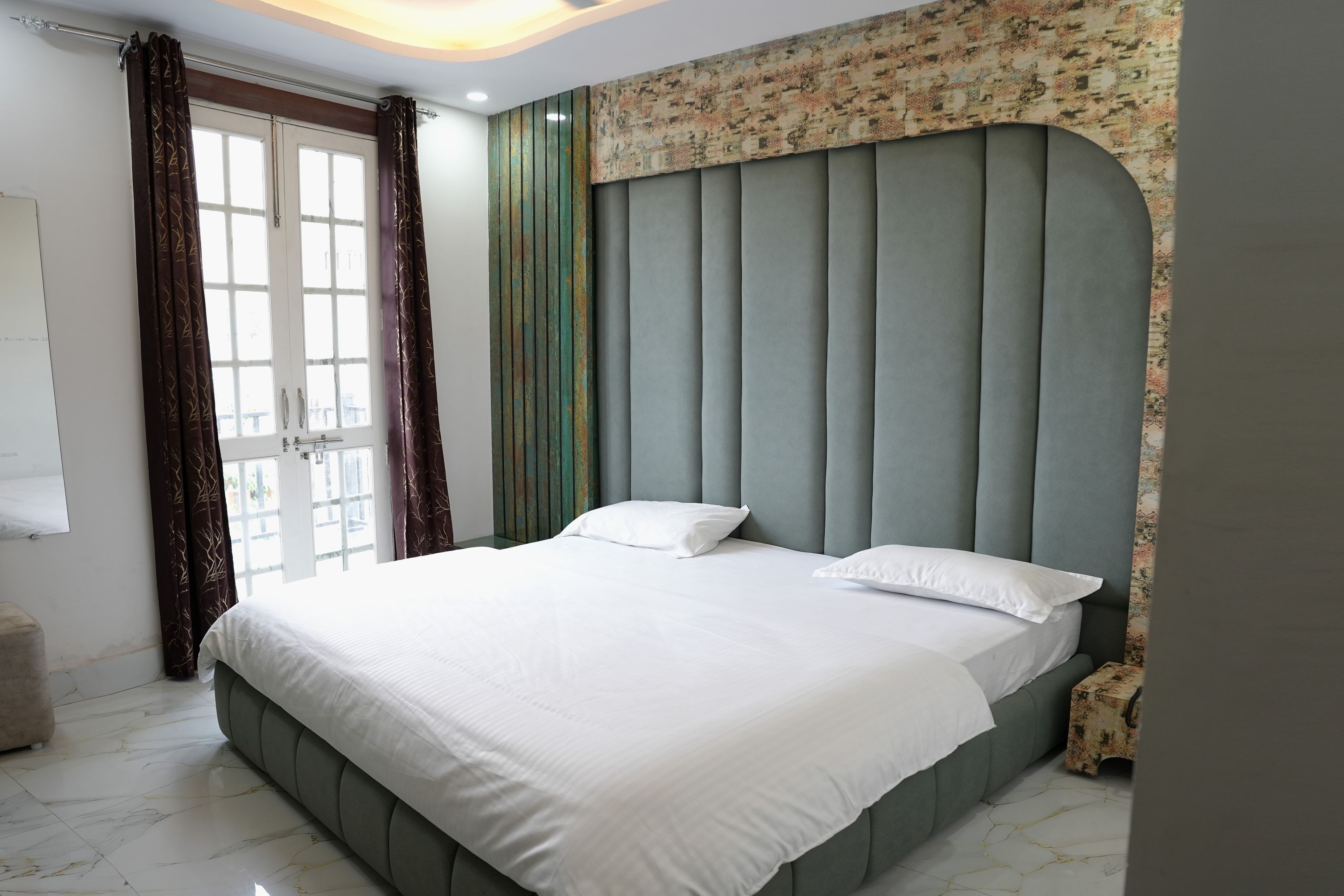 Un dormitorio con cama, cabecera, cortinas y ventana.