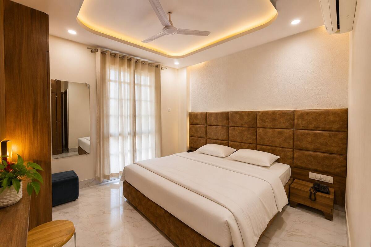 Un dormitorio moderno con una cama grande, un ventilador de techo, una mesita de noche y un espejo.
