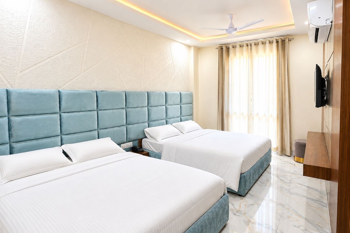 A hotel room with two beds, a ceiling fan, a TV, and a marble floor.