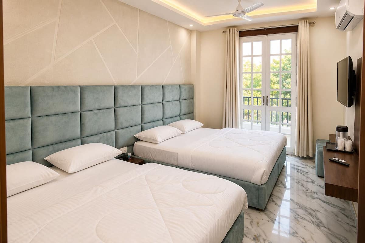 Une chambre d’hôtel avec deux lits, une télévision et un balcon avec des rideaux.