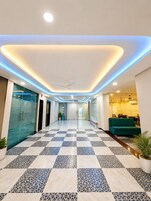 Un hall d’hôtel avec un sol à carreaux, un comptoir d’accueil et un espace salon.