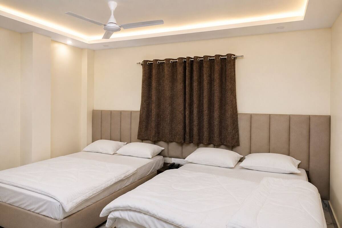 Una habitación de hotel con dos camas, un ventilador de techo y una ventana con cortinas.
