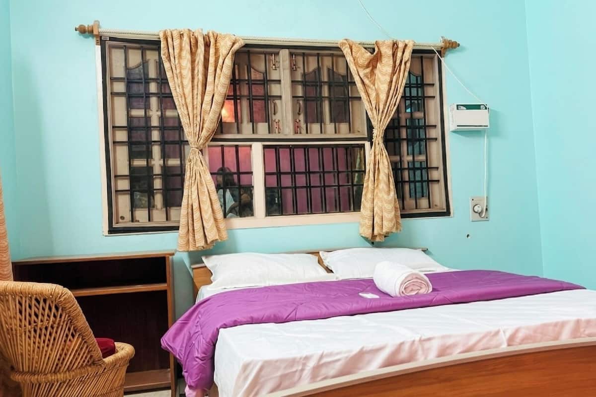 A room with a bed, a chair, a window with curtains, and an air conditioning unit.