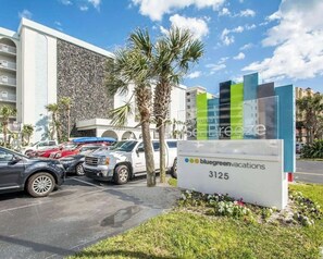 Ein Hotelschild mit der Aufschrift 'BlueGreenVacations 3125' und ein Parkplatz mit mehreren Fahrzeugen.