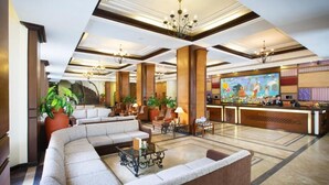A hotel lobby with a curved sofa, a reception desk, and a large mural. - Royal Singi Hotel (Kathmandu)
