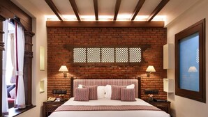 A hotel room with a brick wall, a large bed, two bedside tables with lamps, and a window with a view. - Royal Singi Hotel (Kathmandu)