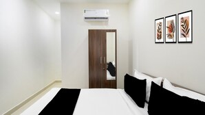 A hotel room with a bed, a wardrobe, an air conditioning unit, and three framed pictures on the wall. - Townhouse Badangpet Crossway Hyderabad (Hyderabad)