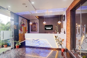Un mostrador de recepción con un cartel que dice 'TOWNHOUSE', plantas en macetas y una pared con un diseño.