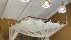 A bed with a canopy, bedside tables, a bench, and hanging lights.