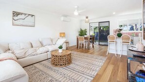 Un salon moderne comprenant un canapé, une table basse ronde en bois et un coin repas avec des chaises et une table.
