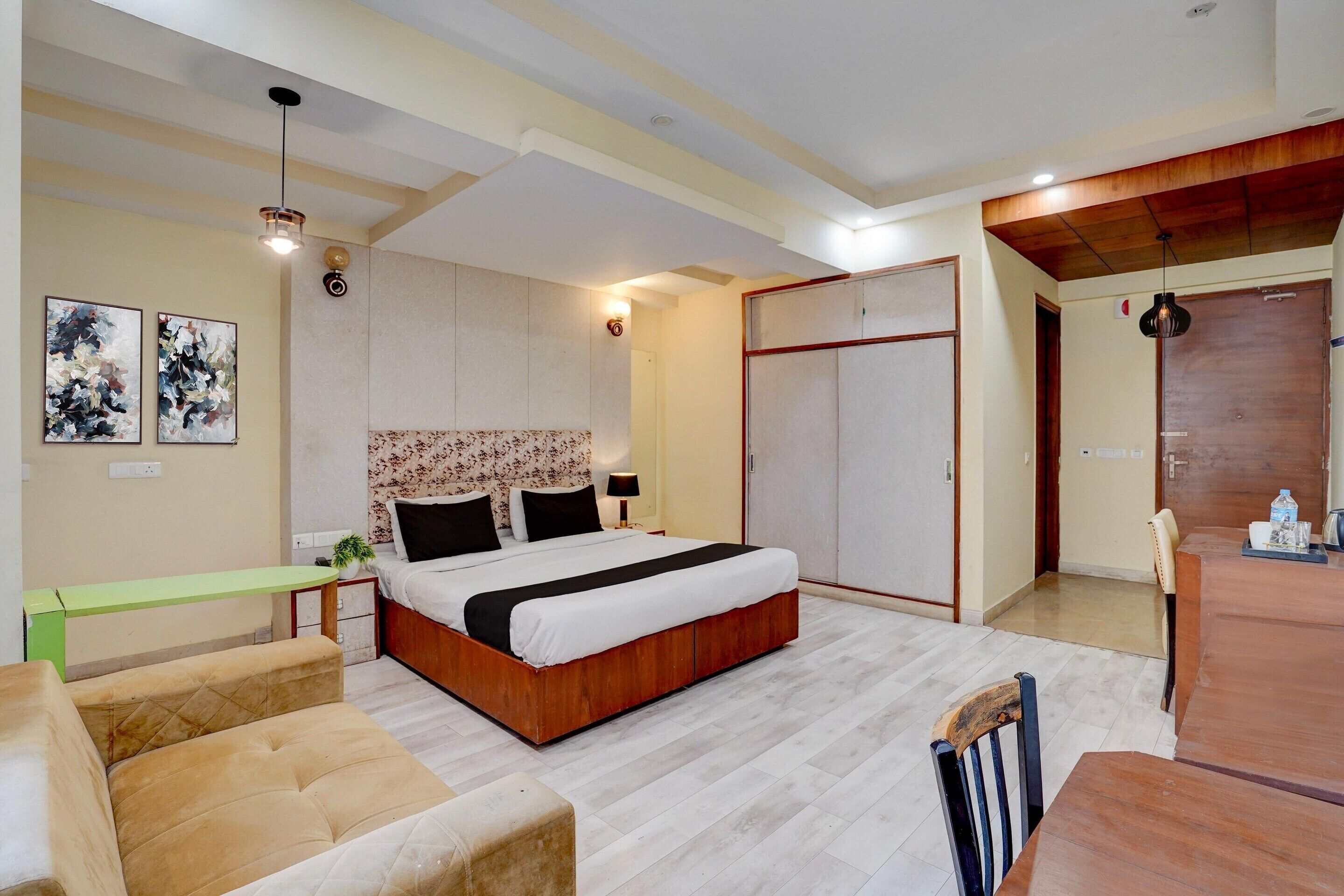 Un dormitorio con cama, mesita de noche, lámpara y un pequeño rincón de descanso.