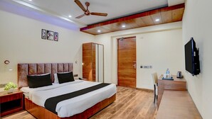 A modern bedroom with a large bed, a wardrobe, a desk with a chair, and a ceiling fan.