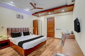 A modern bedroom with a large bed, a wardrobe, a desk with a chair, and a ceiling fan. - Classic With Balcony Near Medanta (Gurugram)