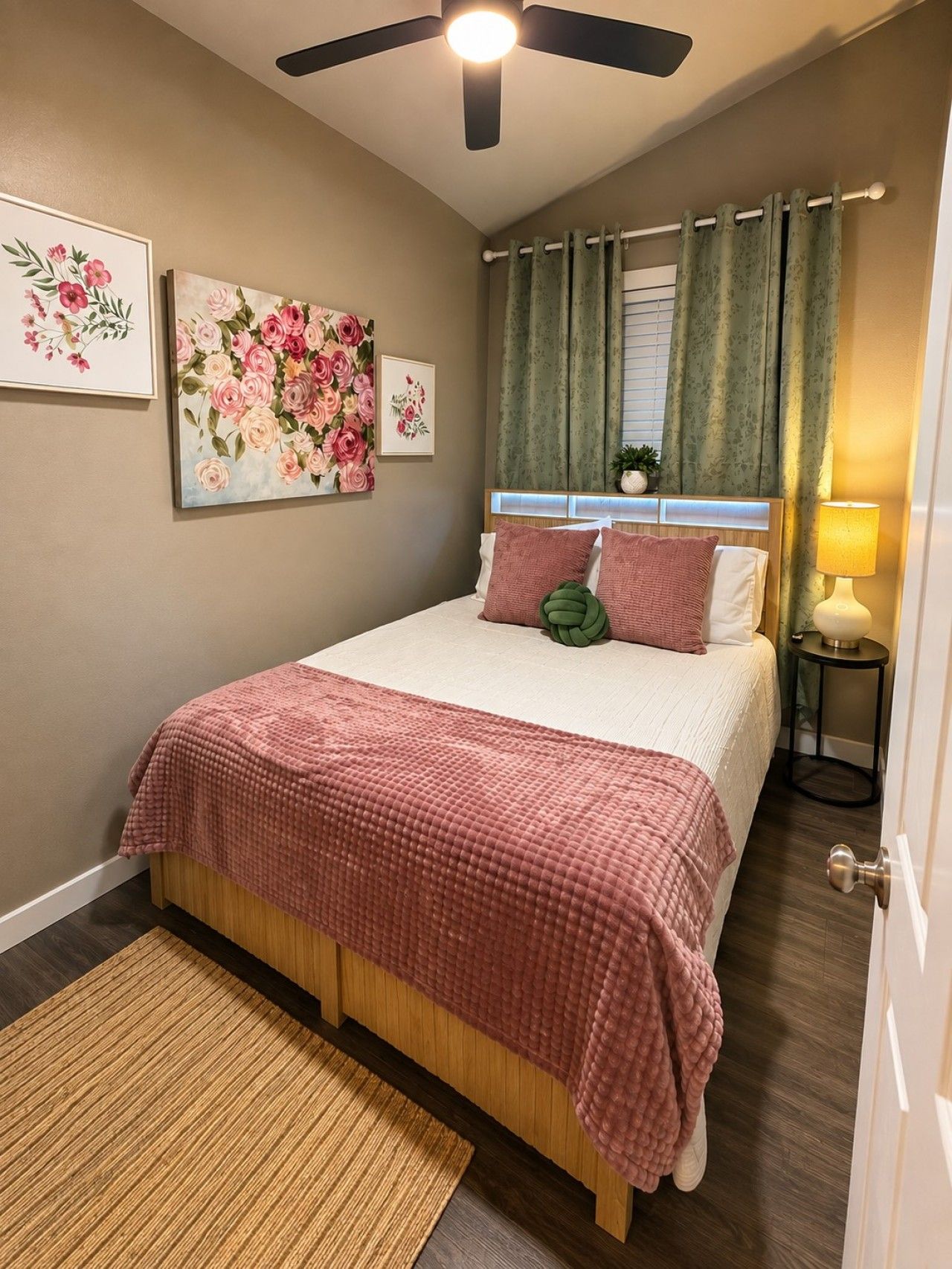 A bedroom with a bed, a ceiling fan, a nightstand, a lamp, and a window with curtains.