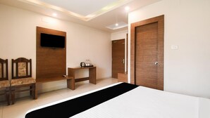 Een hotelkamer met een bed, een aan de muur bevestigde televisie, een bureau met stoel en een kledingkast.