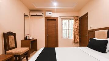 Un dormitorio con cama, escritorio, silla, armario y equipo de aire acondicionado.