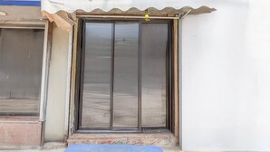 A building entrance with a sliding glass door, a small step leading up to it, and a blue mat at the entrance. - Premium Rupashi Guest House (Shrirampur)