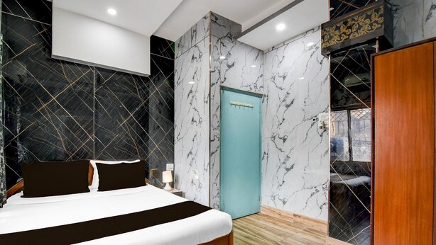 A modern bedroom with a bed, a nightstand, a blue door, and a wardrobe. - Premium Rupashi Guest House (Shrirampur)