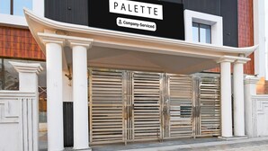 Un bâtiment sur lequel on peut lire l’inscription « PALETTE, entreprise offrant des services » au-dessus d’un ensemble de doubles portes en métal.