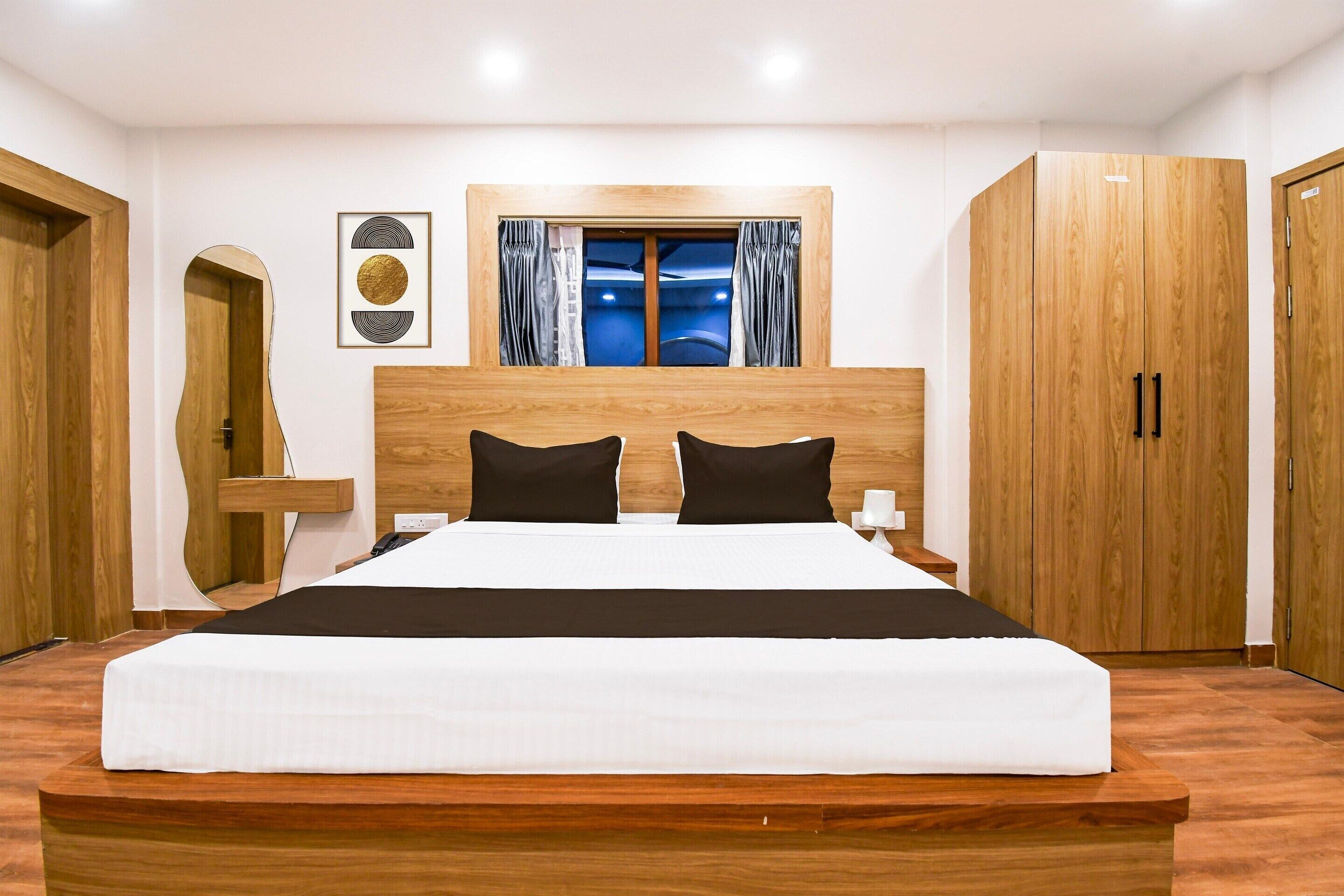 Ein Schlafzimmer mit einem großen Bett, einem Holzkopfteil, zwei Nachttischen, einem Schrank und einem Fenster mit Vorhängen.
