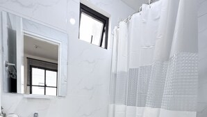 Un baño con lavamanos, inodoro y cortina de ducha blancos.