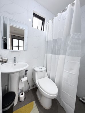 A bathroom with a white sink, toilet, and shower curtain.