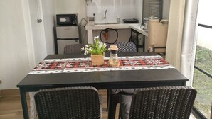Un comedor con una mesa dispuesta para dos, una cocina al fondo y vistas al exterior.