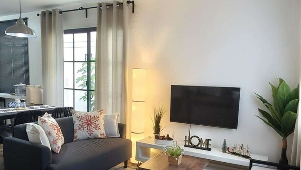 Una sala moderna con sofá, mesa de centro, televisor de pantalla plana y comedor con mesa y sillas.
