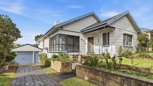 A two-story house with a covered porch, a garage, and a landscaped garden. - Seednest Blue Lake King Bed & BBQ Backyard (Mount Gambier)