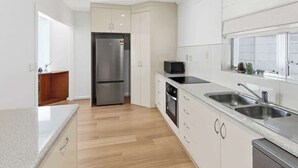 A modern kitchen with a stainless steel refrigerator, a microwave, and a double sink. - Seednest Blue Lake King Bed & BBQ Backyard (Mount Gambier)