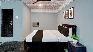 Een slaapkamer met een bed, een plafondventilator, een deur en lijstwerken aan de muur.