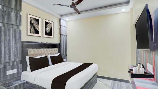 A modern bedroom with a bed, a ceiling fan, and artwork on the wall. - Classic With Balconyamba Palace (Prayagraj)