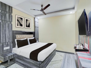 A modern bedroom with a bed, a ceiling fan, and artwork on the wall. - Classic With Balconyamba Palace (Prayagraj)
