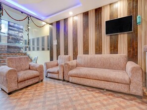 A living room with a sofa set, a flat-screen TV mounted on the wall, and a patterned floor. - Classic With Balconyamba Palace (Prayagraj)