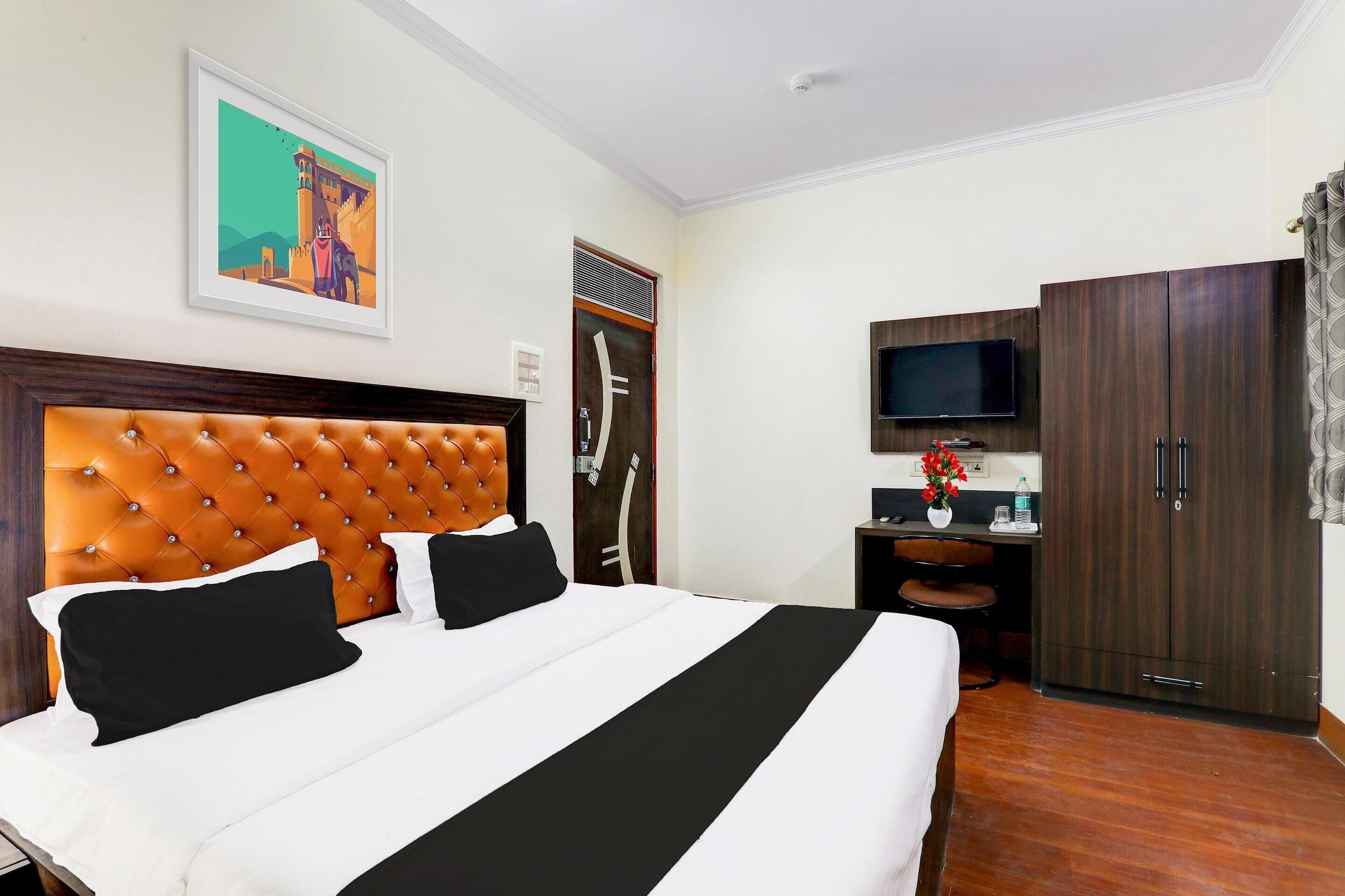 A hotel room with a large bed, a television, a wardrobe, and a desk with a chair.