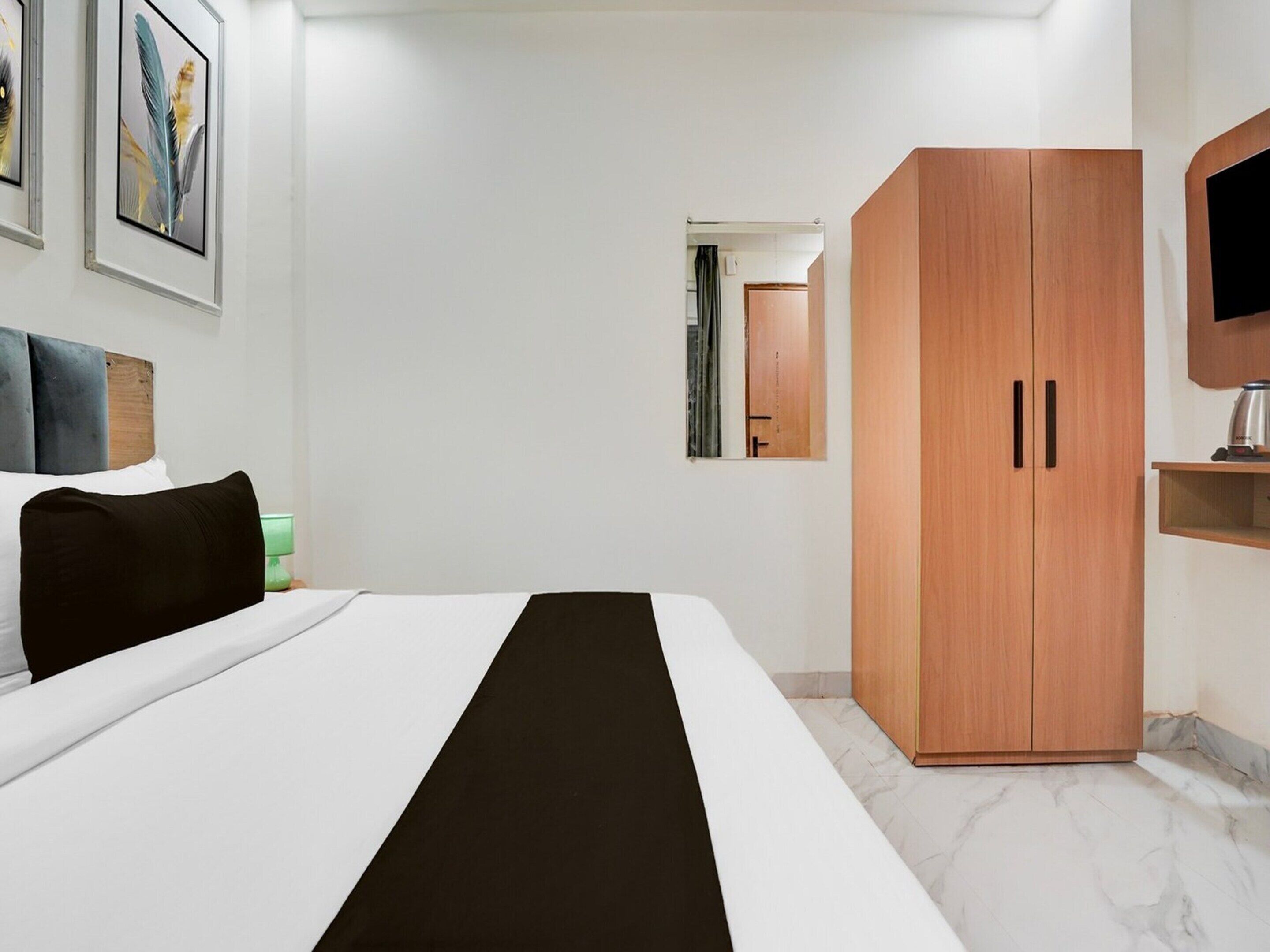 Een hotelkamer met een bed, een kledingkast, een televisie en een spiegel.