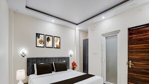 Un dormitorio con cama, mesitas de noche, una lámpara de pared y una puerta.