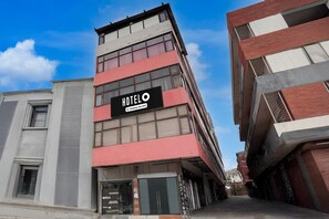 En hotellbyggnad med flera våningar, ett tydligt och väl synligt hotellskylt, stora fönster och en modern arkitektonisk design.