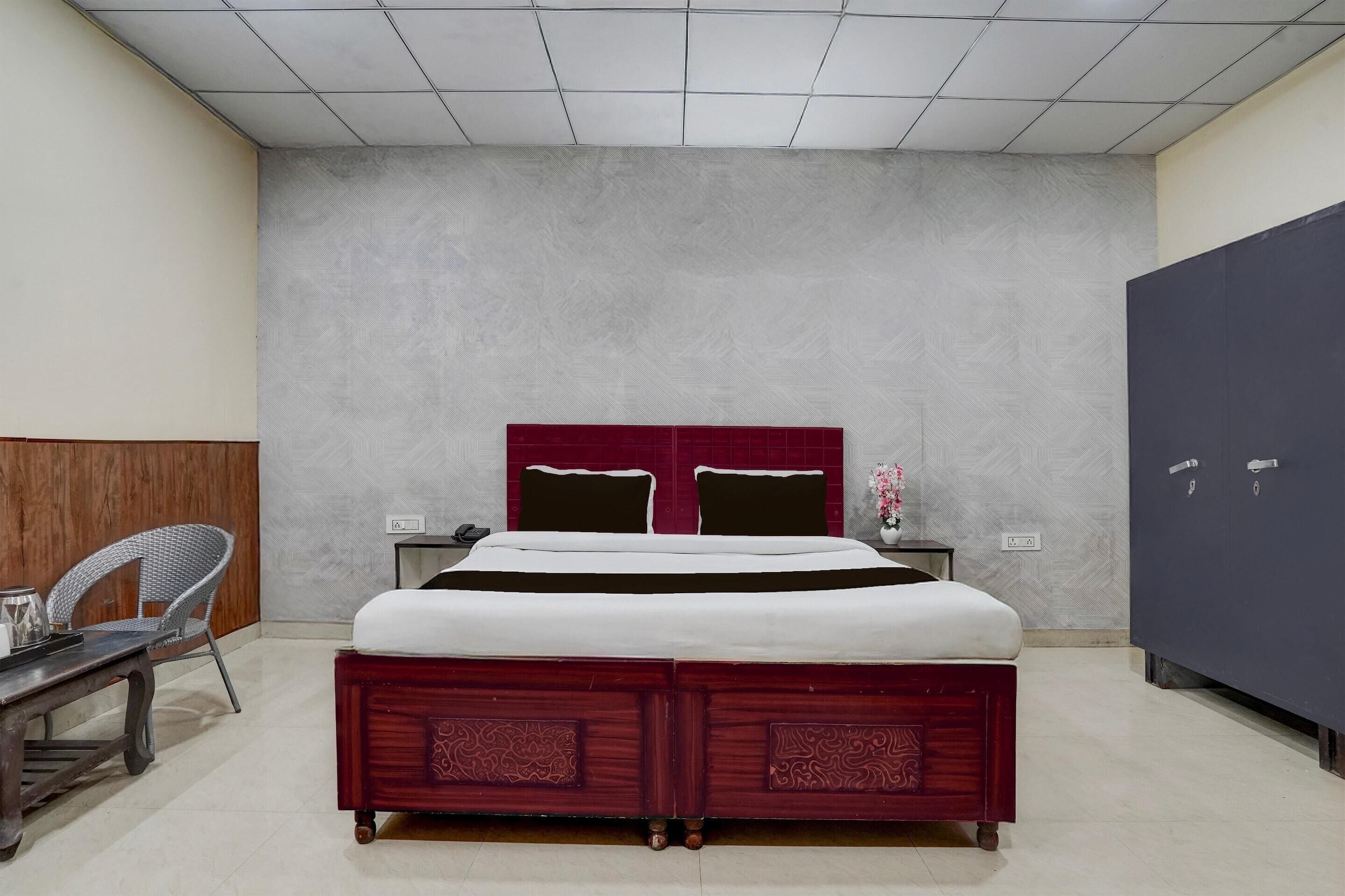 Ein Schlafzimmer mit einem großen Bett, einem Schreibtisch mit Stuhl, einem Kleiderschrank und einem Nachttisch mit Lampe.